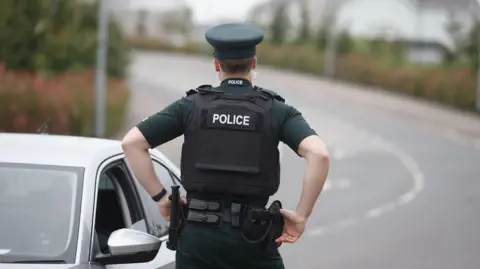 Pacemaker Police officer facing away from the camera speaking to someone through their car window 