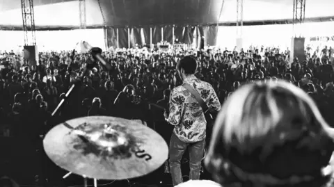 Ricardo Cenci Isaac Neilson performing on stage in front of thousands of people at Y Not Festival in Pikehall, Derbyshire