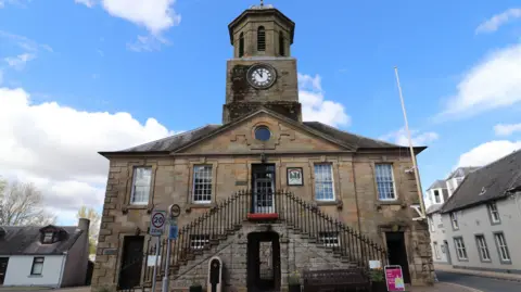 The sandstone Sanquhar Tolbooth building with a tower on the top and two sets of stairs leading to its raised front door