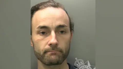 A police image of a man with dark hair and stubble