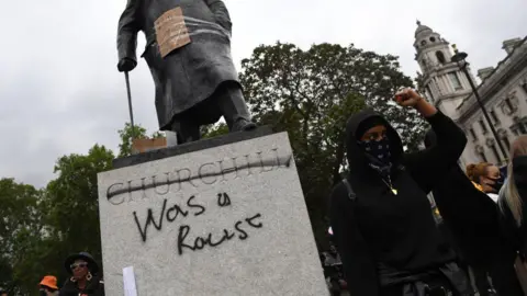 Getty Images Protesters gathering in Parliament Square Garden around the statue of Sir Winston - his name is crossed out and the words "was a racist" have been added in graffiti.