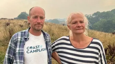 Ed Gaskarth and Verity Bellamy own the Coast and Camplight glamping site at Stainsacre. Ed is wearin ga blue and white check shirt over a white t-shirt while Verity is wearing a blue and white striped blouse.