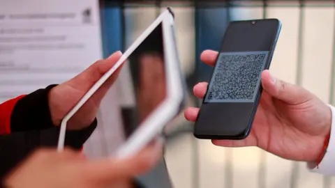 Getty Images A security officer scans a mobile phone with a QR code ticket