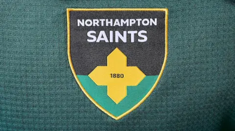 Northampton Saints New Northampton Saints crest which is black and green with a gold cross across the middle