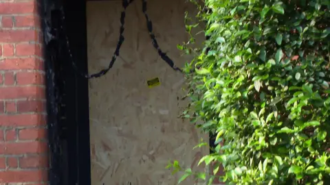 A boarded-up door at the home where a fire occurred