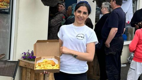 A woman holding a box of fish and chips