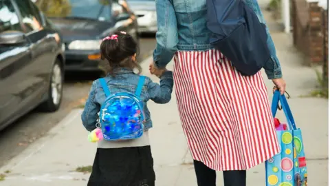 Getty Images Mother and daughter walking to school stock photo
