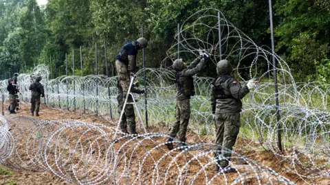 Getty Images Polish soldier lay razor wire along the border with Belarus