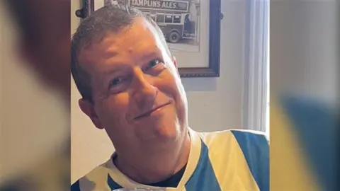 Russell Jeffer A man wearing a blue and white Brighton & Hove Albion shirt smiles for the camera.