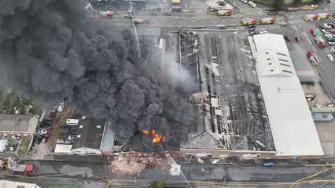 West Midlands Fire Service An aerial shot of a factory fire with large amounts of grey smoke