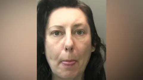 Custody picture of Samantha Gardiner she has log dark hair and is sticking her tongue out.