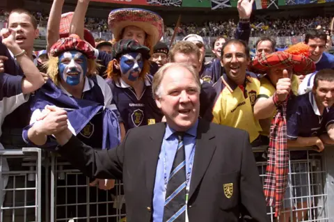 Getty Images Scotland fans at France 1998 with manager Craig Brown. He is smiling and wearing a suit.