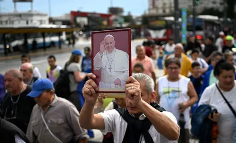 AFP A man holds a portrait of Pope Francis at a mass for his healing in Constitution Square, Buenos Aires, Argentina, on 24 February 2025.