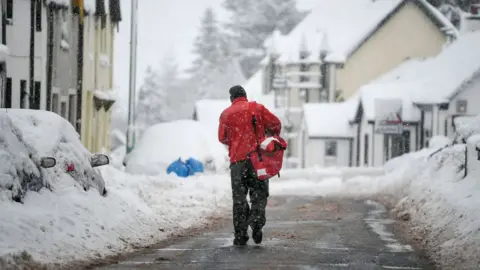 Getty Images Post man delivering post in the snow.