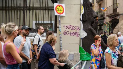 Marc Asensio/NurPhoto A graffiti against tourism appears in one of the streets that residents decorate during the Gracia Festival, the most popular in the city, in Barcelona, Spain, on August 16, 2023