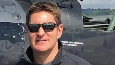 Dave Walton Dave Walton has brown hair and is wearing sunglasses and is standing in front of a black aircraft.