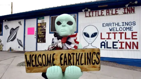 Getty Images An alien-like statue displays a sign welcoming guests to the Little A'le' Inn restaurant and gift shop in Rachel, Nevada