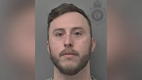 Humberside Police A police custody photograph of a man with short brown hair, a beard and stubble looking into the camera with a serious expression against a grey background.