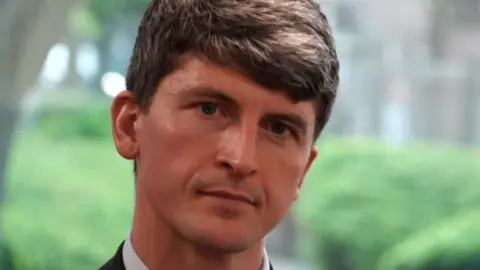 A man with short dark brown hair.