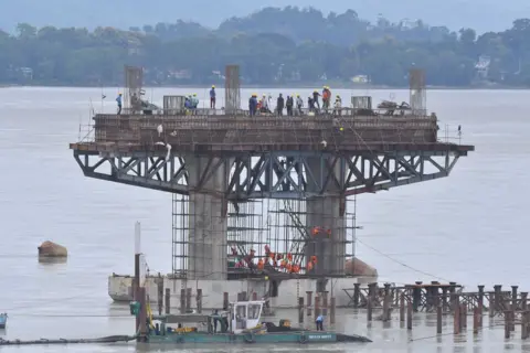 Getty Images Workers are working on the construction of a bridge over the Brahmaputra River in Guwahati, India, on July 23, 2024.
