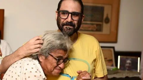 Sayed Hassan/Getty Images Alaa Abd El Fattah pictured hugging his mother after being released as a hostage wearing a yellow t-shirt