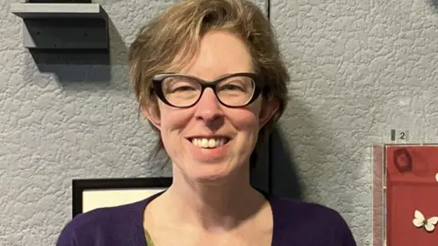 KATIE KING Laura McCoy, who has short brown hair and is wearing glasses and a purple top.