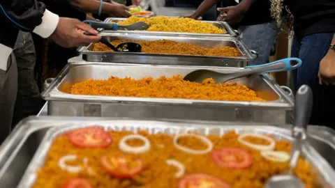 Jon Wright/BBC A row of metal serving dishes with different rice dishes in each.