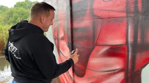 Hollie Cole/BBC Nathan Murdoch paints a mural