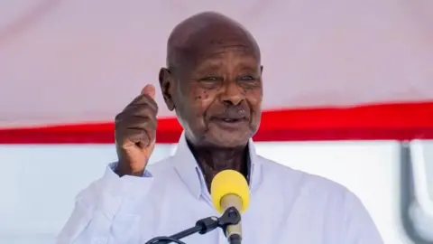 Yoweri Museveni, in white shirt and with fist raised, speaks in Kampala, Uganda, on 5 June 2025
