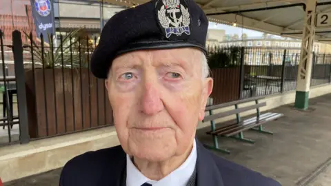 BBC Stan Ford on the platform of Bath Railway station. He is wearing his cap and jacket with war medals