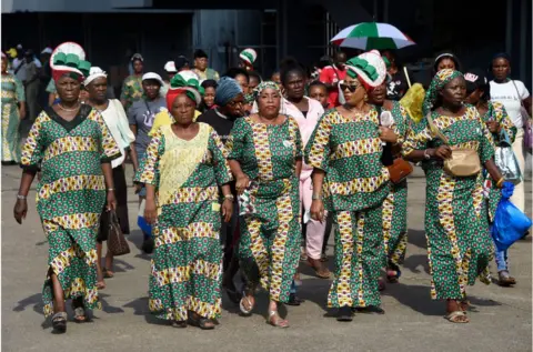 AFP Nigerian women wearing the same green and yellow printed dresses walking the streets.
