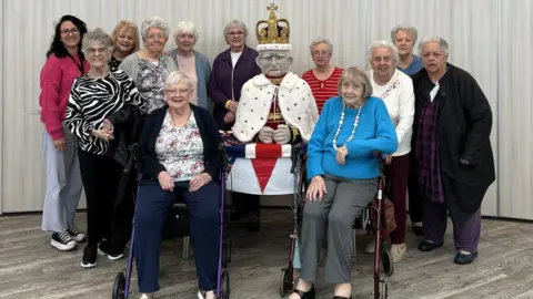 Extra Care Charitable Trust The Knit and Natter group with the model of King Charles