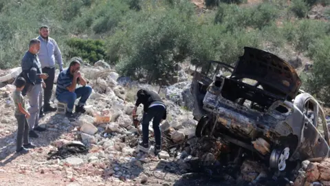 EPA Palestinians inspect a car set on fire by Israeli settlers near the West Bank City of Salfit