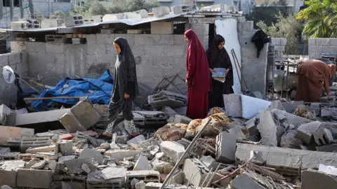 Reuters Women inspect as a house damaged in an Israeli strike lies in ruin, amid the ongoing conflict between Israel and Hamas, in Rafah