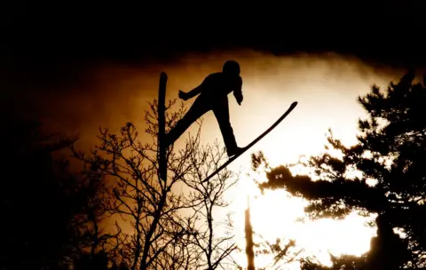 Getty Images silhouetted figure jumping with skis