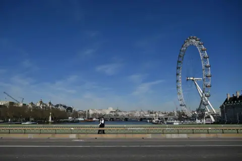 Getty Images Two police officers walk over a deserted Westminster Bridge with the London Eye seen behind, in central London, 23 March 2020