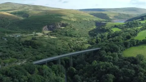 An aerial view over Dartmoor with the Meldon Viaduct in the foreground and the Meldon reservoir in the distance.