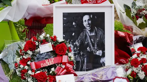 PA Media A black and white framed photo of a smiling Jota, surrounded by red and white wreath designed, among tributes left for Jota at Anfield