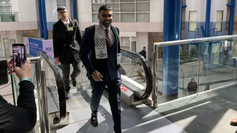 Mr Yaqoob in a blue suit smiling