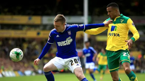 PA Media Freddie Sears, wearing Ipswich's blue strip, holds off Norwich City's Martin Olsson, who wears their green and yellow kit, during a game.