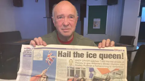 Jerry holds up a local news paper with the words "Hail the ice queen".
