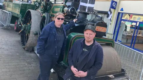 two people stood in front of the the City of Truro Steam Roller 