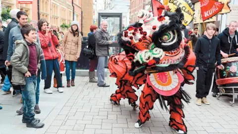 RBWM A red 'lion' dance dances in front of smiling onlookers.