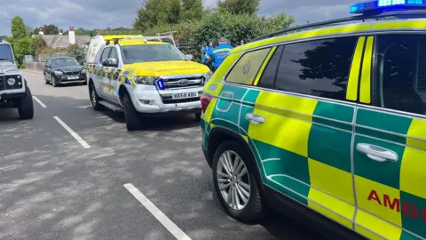 A coastguard vehicle and an ambulance vehicle in front of it on a road. 