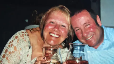 Supplied Robert and his wife Aileen smile at the camera and both hold a glass of beer.