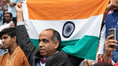 Getty Images A supporter of Prime Minister Narendra Modi holding the Indian flag during the Howdy Modi event in Houston in 2019. 