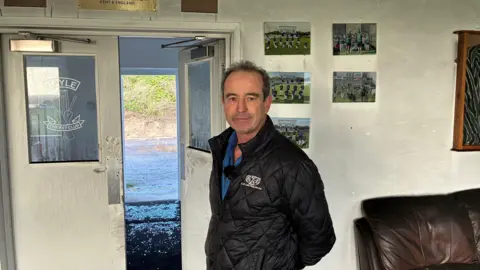 A man standing in front of a doorway looking towards the camera