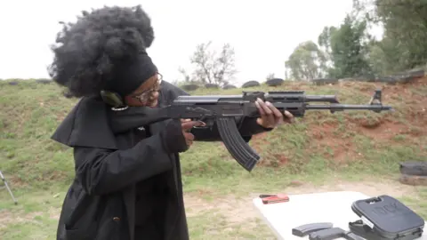 Woman dressed in black holding gun at a shooting range