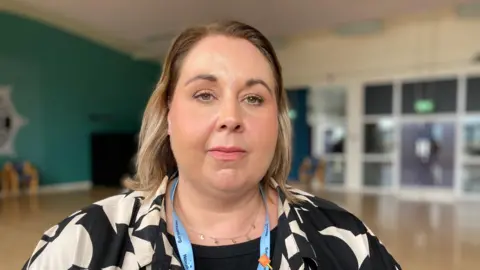 BBC Jan Winton, from Nexus, stares into the camera. She has shoulder-length blond hair and is wearing a black and cream top.