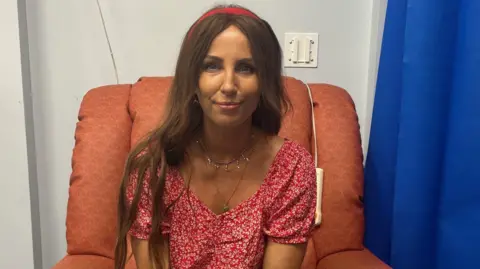 A woman in a red dress with long brown hair and a red head band
